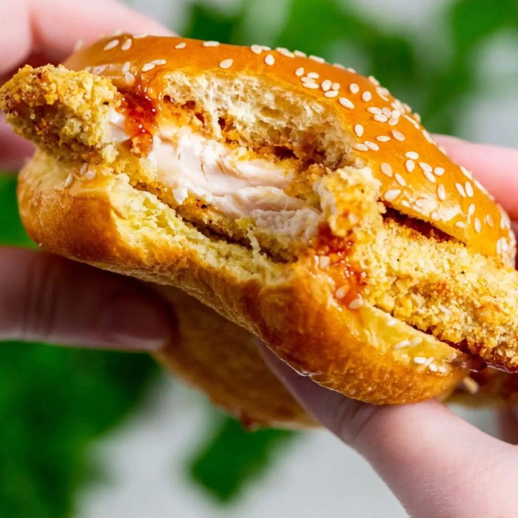 Delicious Chicken Air Fryer Recipes For Busy Weeknights Close Up of a Chicken Katsu Sandwich with a Bite Taken From it In Between a Person's Hands