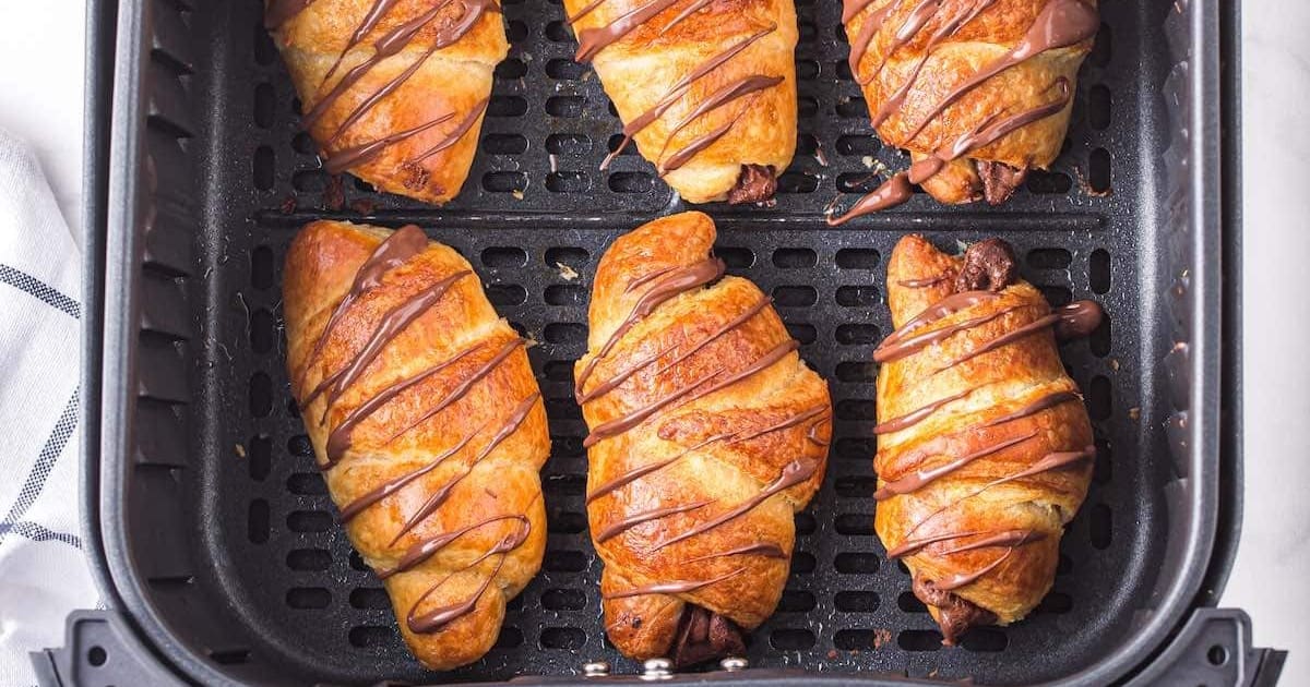 Air Fryer Croissants in an Air Fryer Basket Drizzled with Nutella