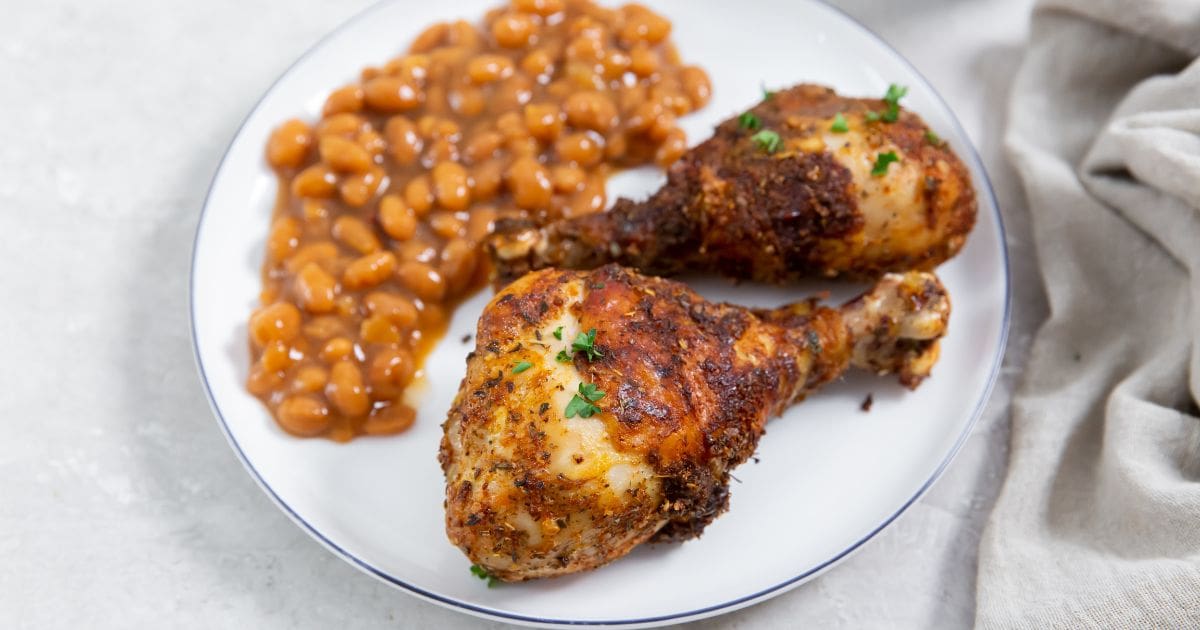 Chicken Recipes That Prove Easy Air Fryer Chicken Legs with Dry Rub on a Plate with Baked Beans