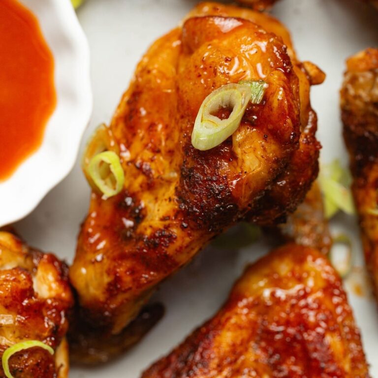 Cozy Fall Chicken Air Fryer Recipes Close Up of a Full Buffalo Wing on a Plate Next to a Small Ramekin of Buffalo Sauce
