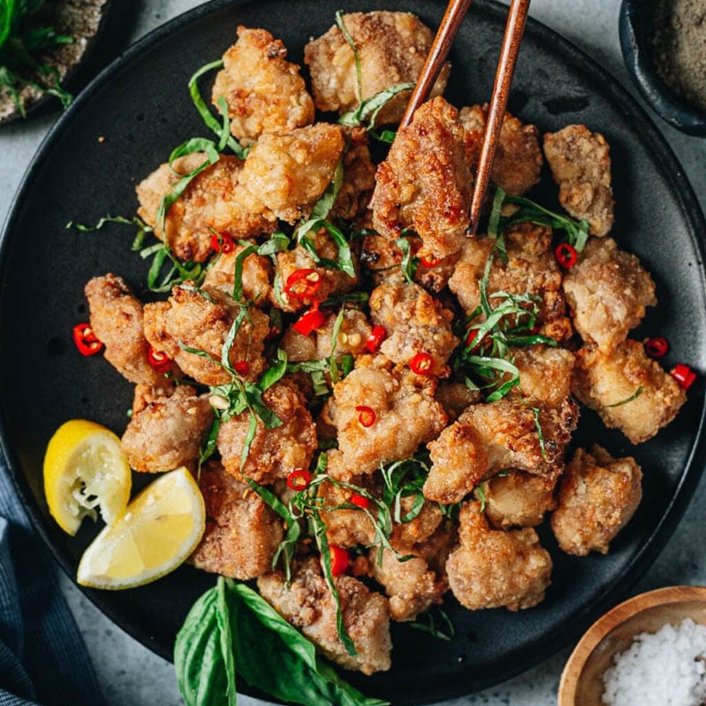 Chicken Recipes to Shake Up Your Dinner Close Up of a Piece of Chicken i Being Held with Chopsticks Above a Plate of Chicken Bites