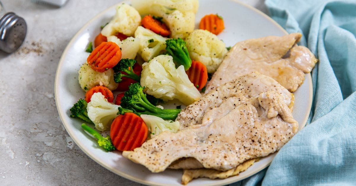 Easy Chicken Air Fryer Recipes Ready in 30 Minutes Air Fryer Thin-Sliced Chicken Breast with Steamed Veggies on a White Plate 