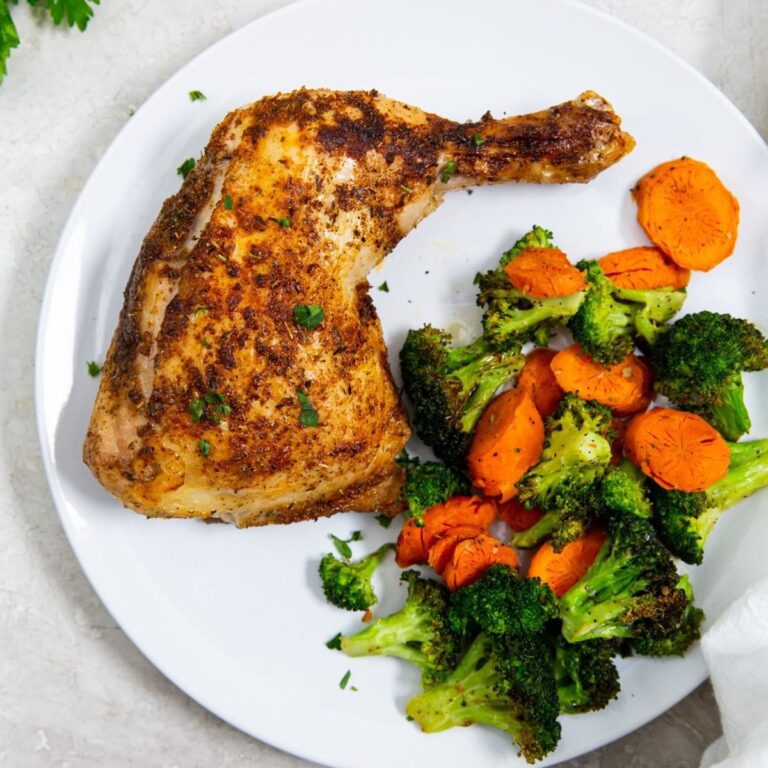 Air Fryer Chicken Recipes to Help You Lose Weight After the Holidays a Cooked Chicken Quarter on a Plate with Steamed Veggies