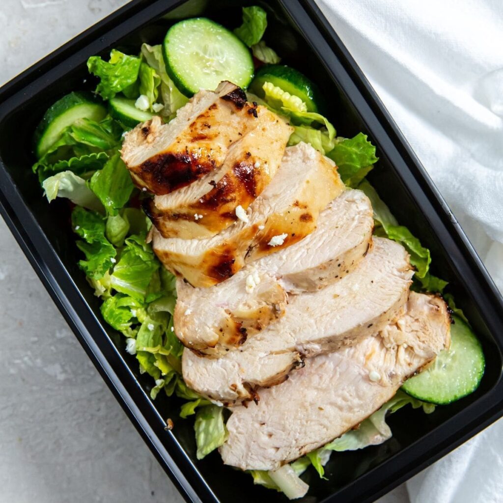 Quick Chicken Air Fryer Recipes a Black Meal Prep Container Filled with Salad and Topped with Sliced Italian Chicken