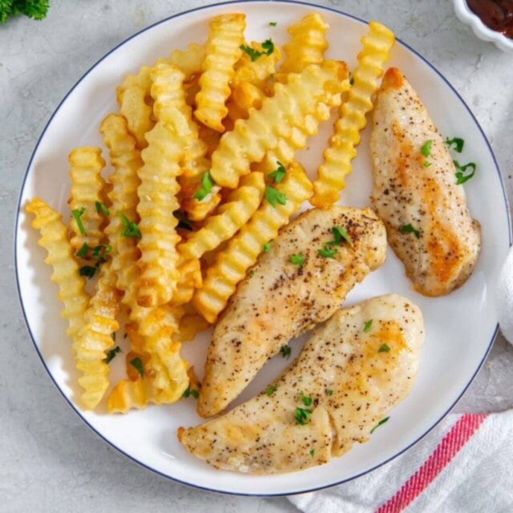 Kid-Friendly Air Fryer Recipes Chicken Strips and Crinckle Fries on a White Plate next to a White Tea Towel on a County