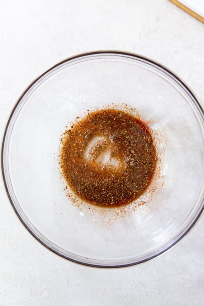 Air Fryer Chicken Breast Strips Gray background with clear mixing bowl with ingredients mixed together