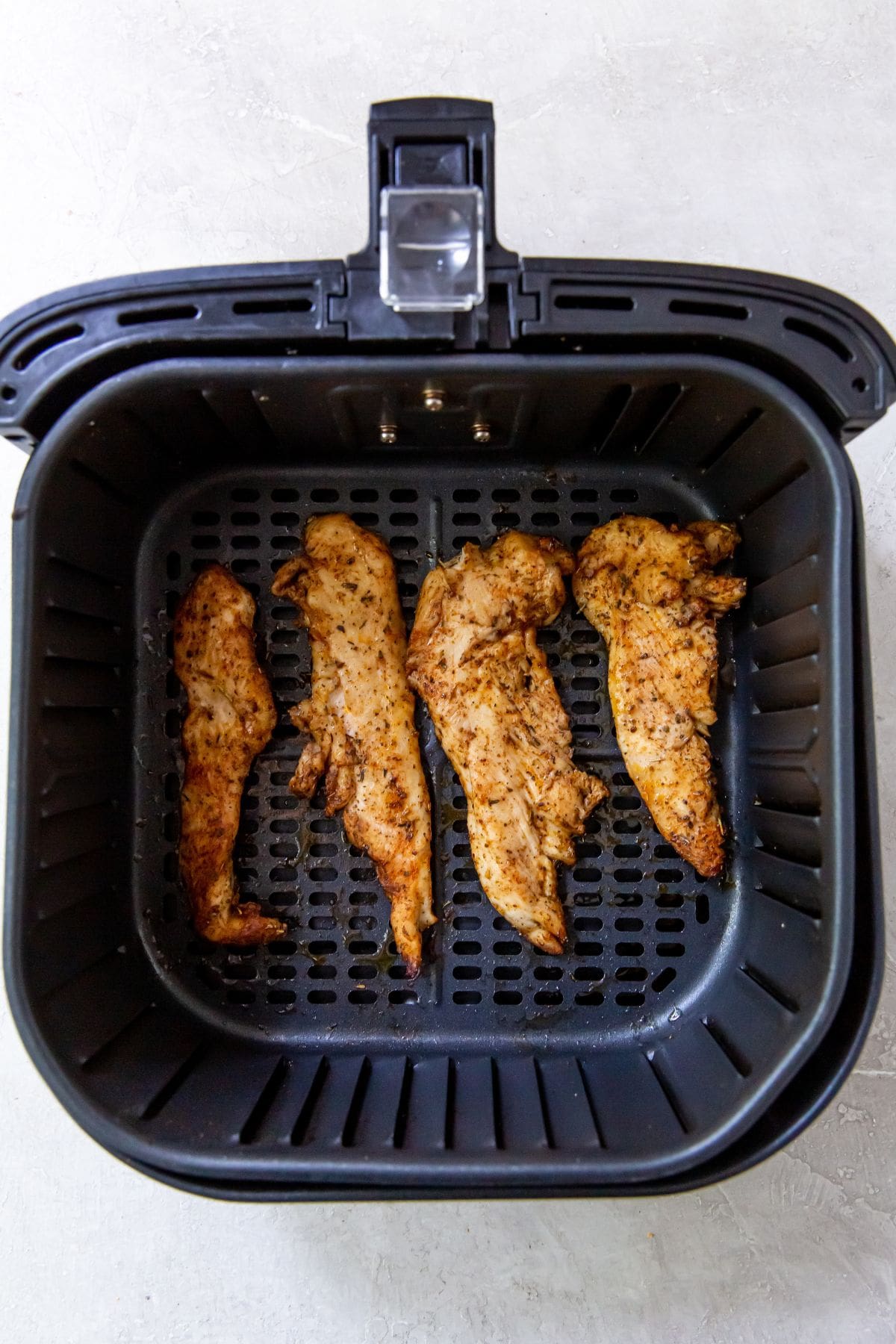 Air Fryer Chicken Breast Strips Black Air Fryer with raw chicken inside cooked