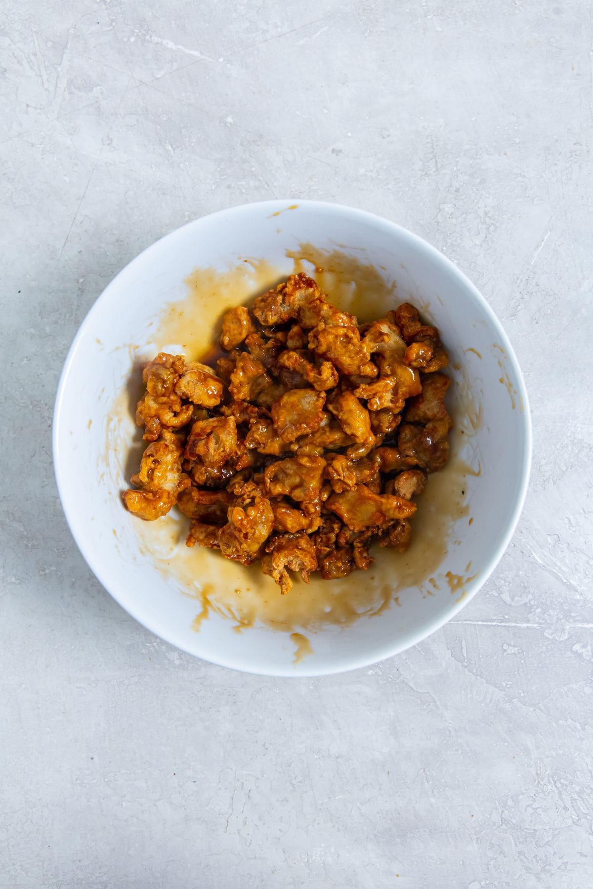 Air Fryer Trader Joe&rsquo;s Orange Chicken white bowl with chicken and sauce toss inside