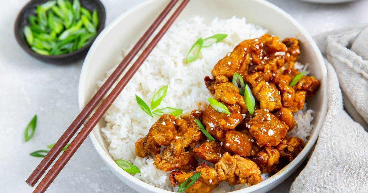 Air Fryer Trader Joe&rsquo;s Orange Chicken a Bowl of Rice Topped with Orange Chicken and Chopsticks