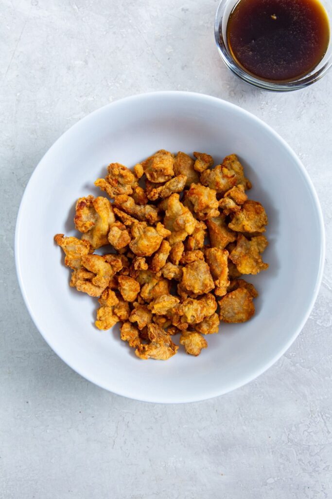 Air Fryer Trader Joe&rsquo;s Orange Chicken white bowl with chicken inside the sauce on the side