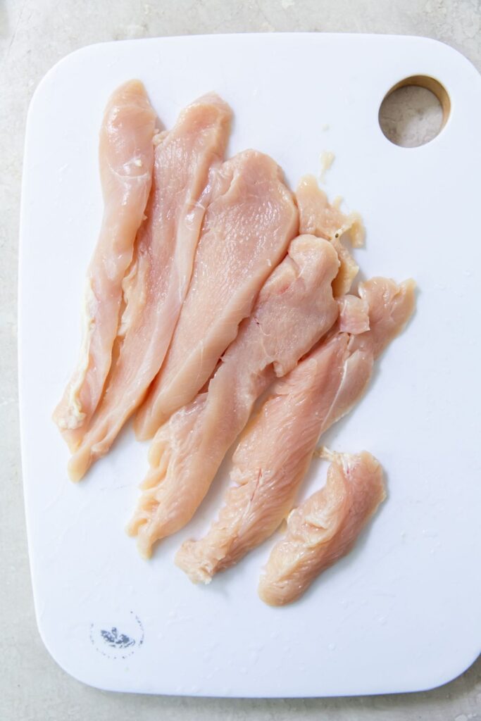 Air Fryer Chicken Breast Strips White cutting board with chicken breast cut into strips