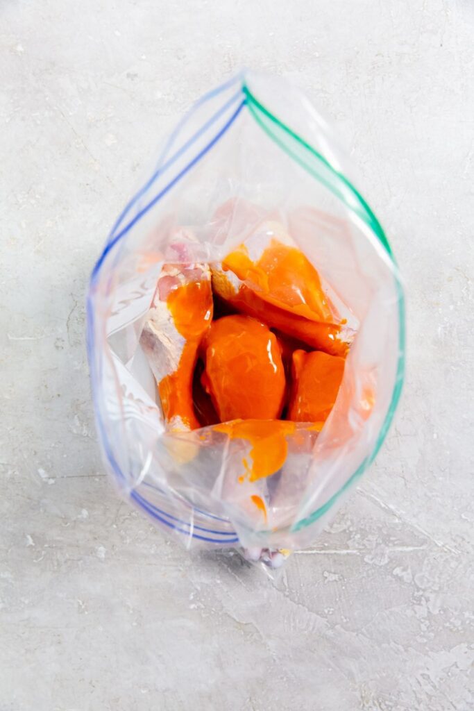 Air Fryer Buffalo Chicken Legs chicken and buffalo sauce inside a ziplock bag