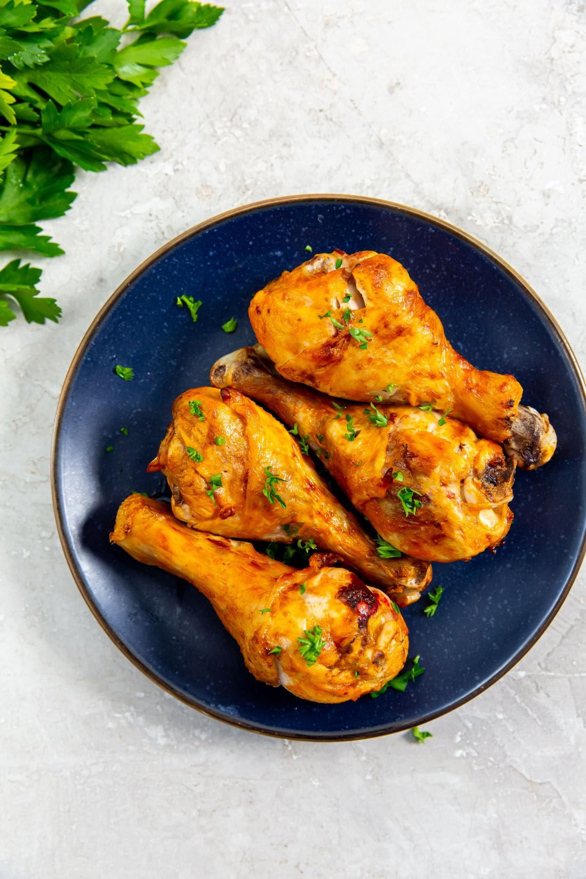 Air Fryer Buffalo Chicken Legs blue plate with chicken and parsley in the back