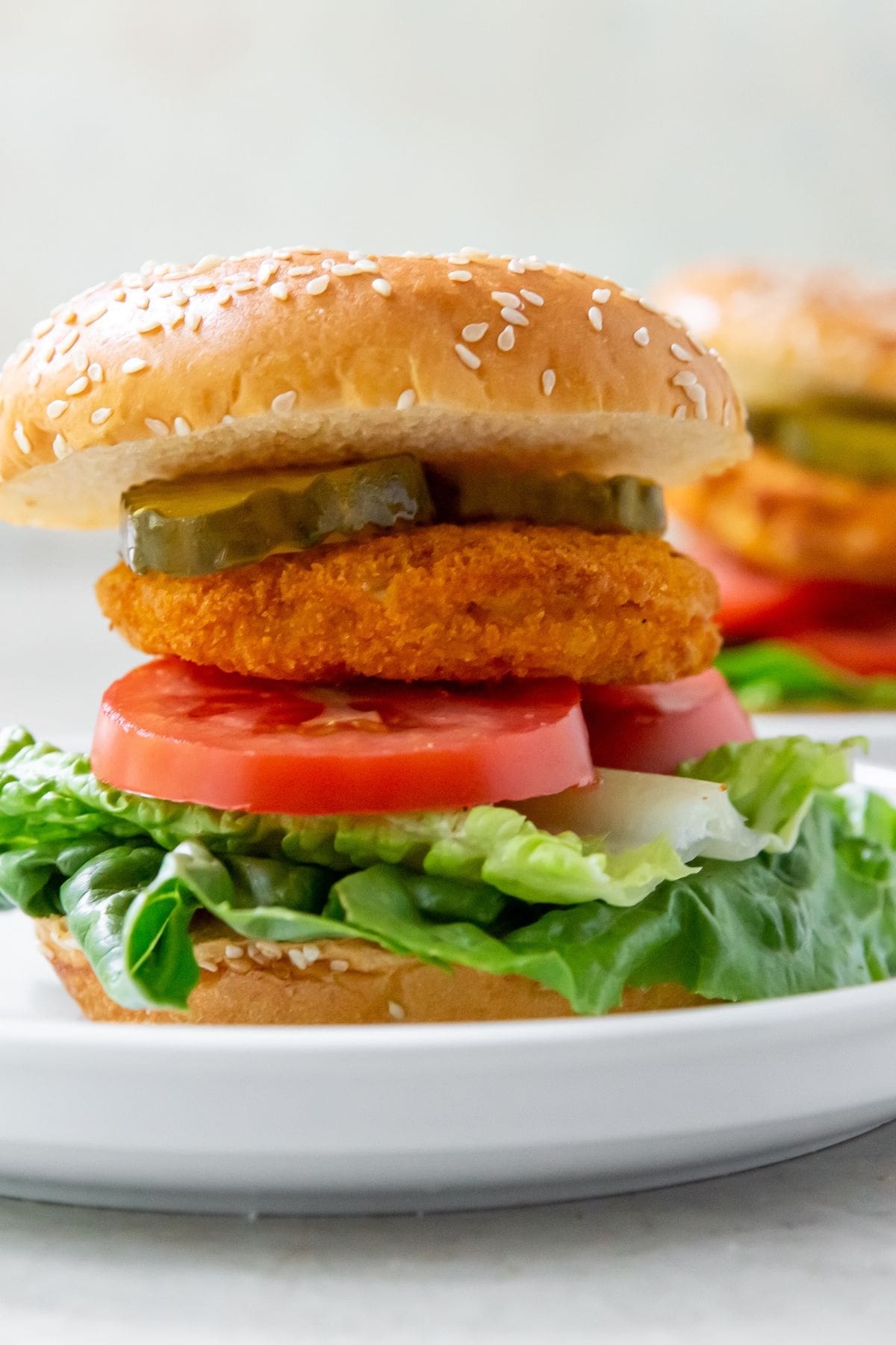 Air Fryer Chicken Patty White plate with Hamburger bun that has tomato lettuce chicken Pattie and pickles