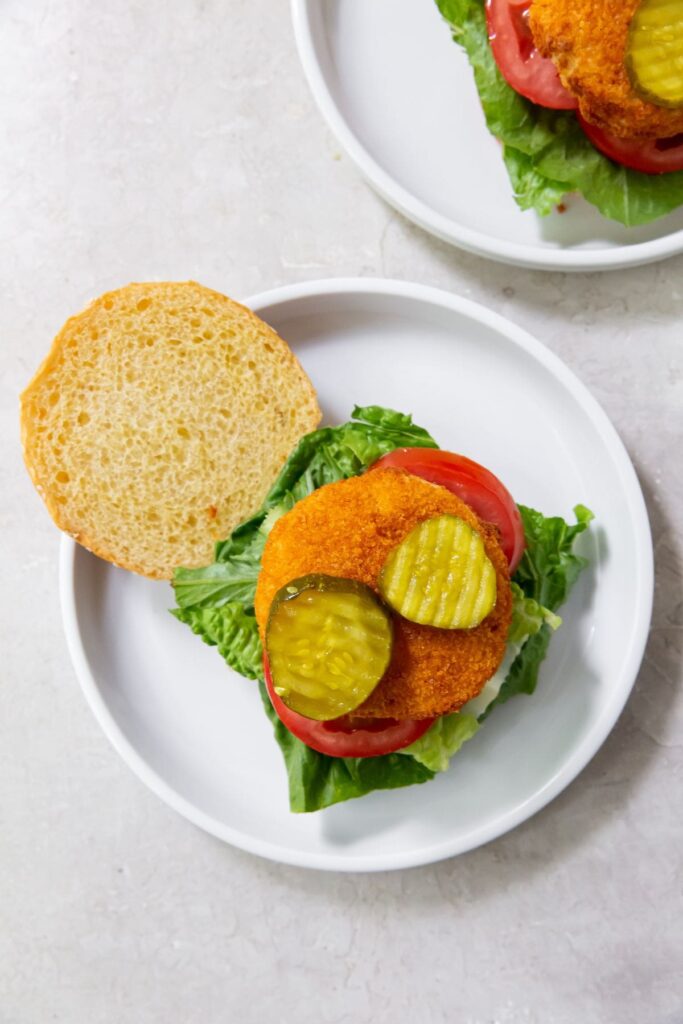 Air Fryer Chicken Patty White plate with Hamburger bun that has tomato lettuce chicken Pattie and pickles