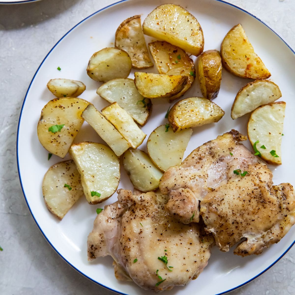 Air Fryer Chicken Thighs and Potatoes plate with chicken thighs and potatoes on it.
