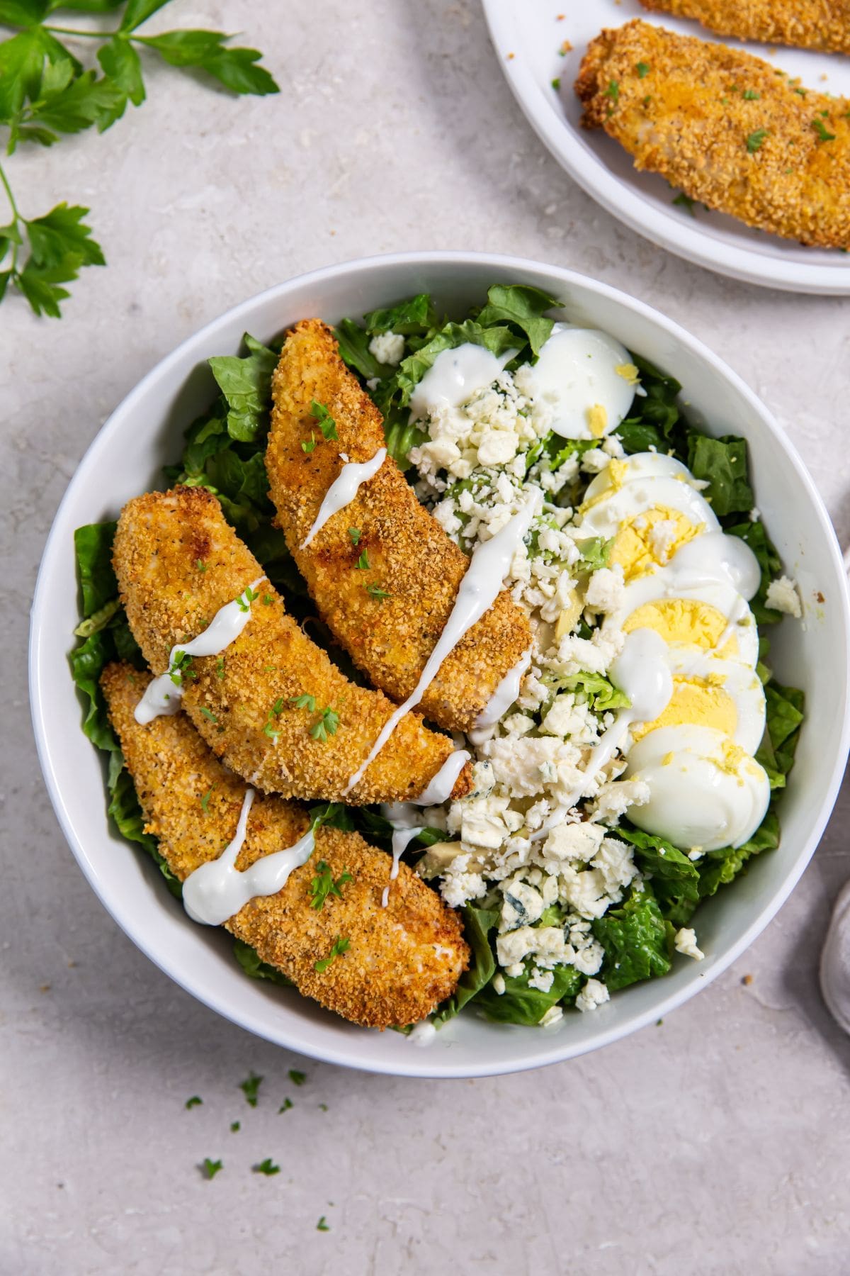 Air Fryer Shake N Bake Chicken Tenders bowl with salad and chicken. chicken in the background
