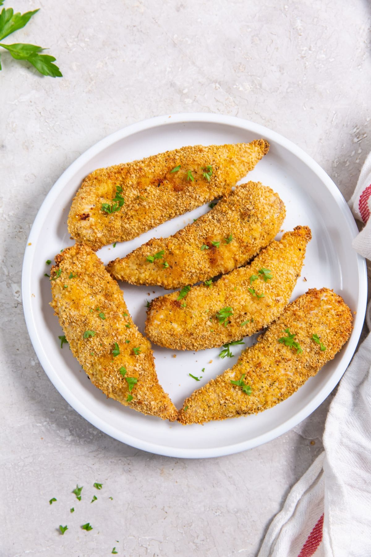 Air Fryer Shake N Bake Chicken Tenders plate with chicken tenders. parsley sprinkled on top and in the back