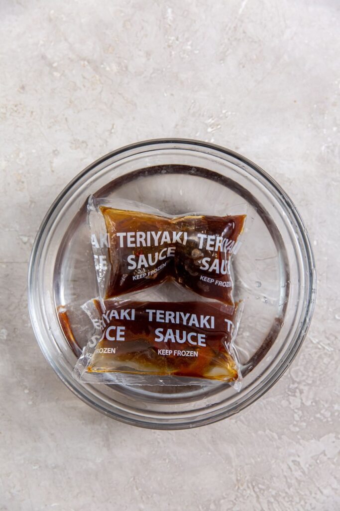 Air Fryer Trader Joe&rsquo;s BBQ Teriyaki Chicken a Small Packet of Teriyaki Sauce Sitting in a Bowl of Warm Water