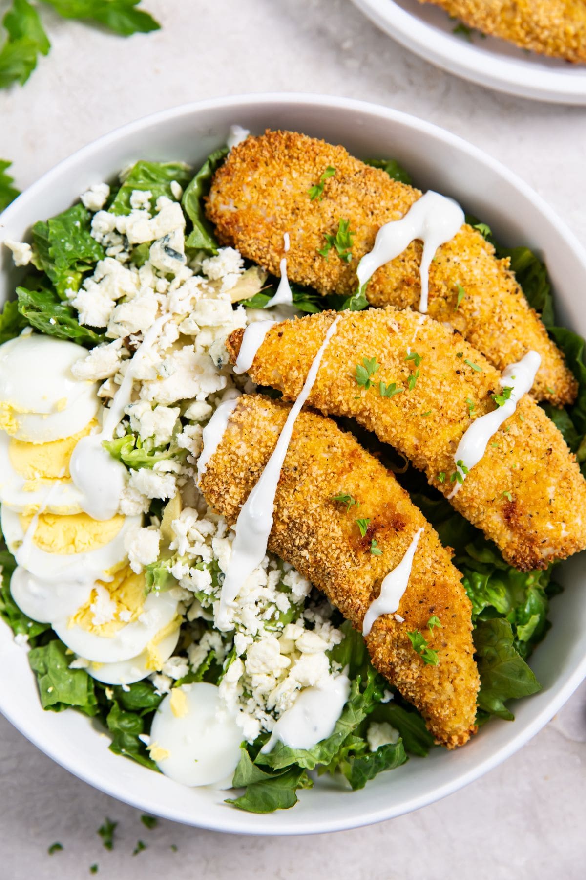 Air Fryer Shake N Bake Chicken Tenders bowl with salad and chicken. chicken in the background