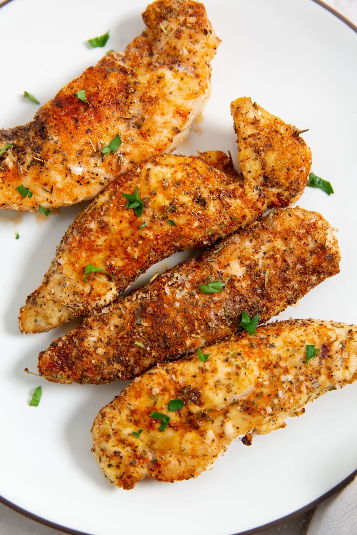 Air Fryer Blackened Chicken Tenders white plate with chicken tenders with parsley.