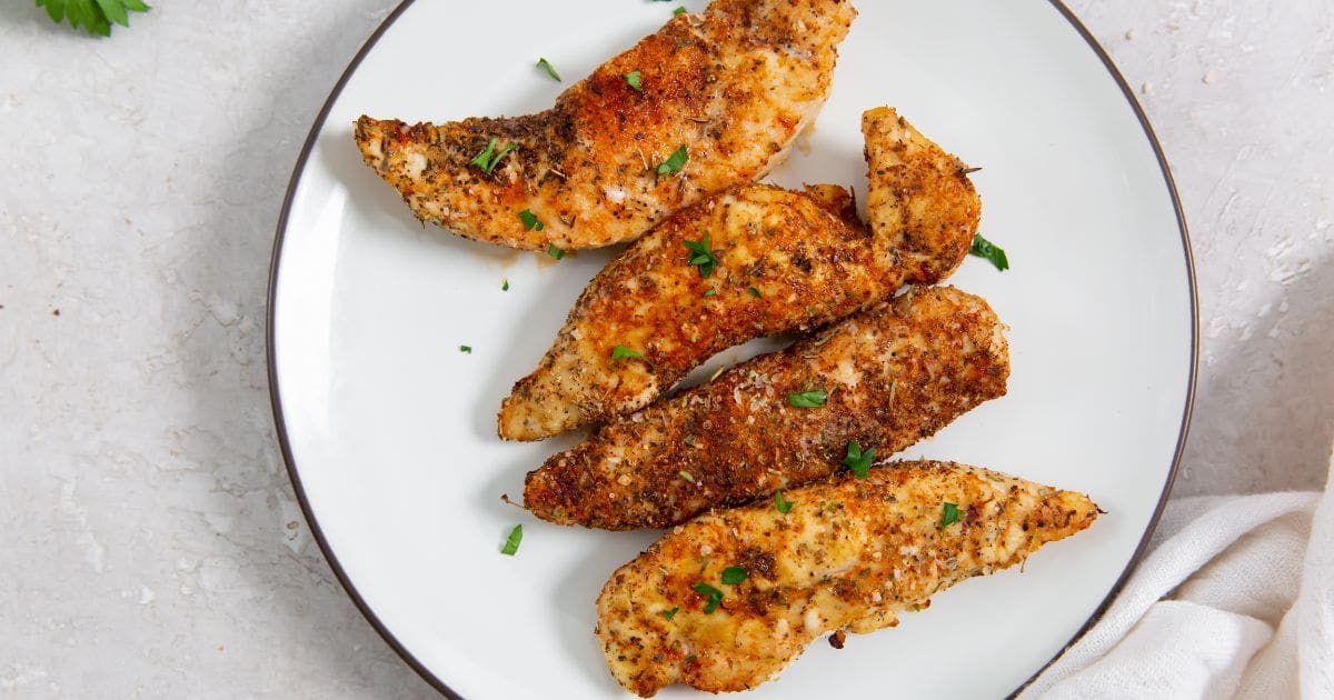 Air Fryer Blackened Chicken Tenders on a White Plate with a Towel Next to it