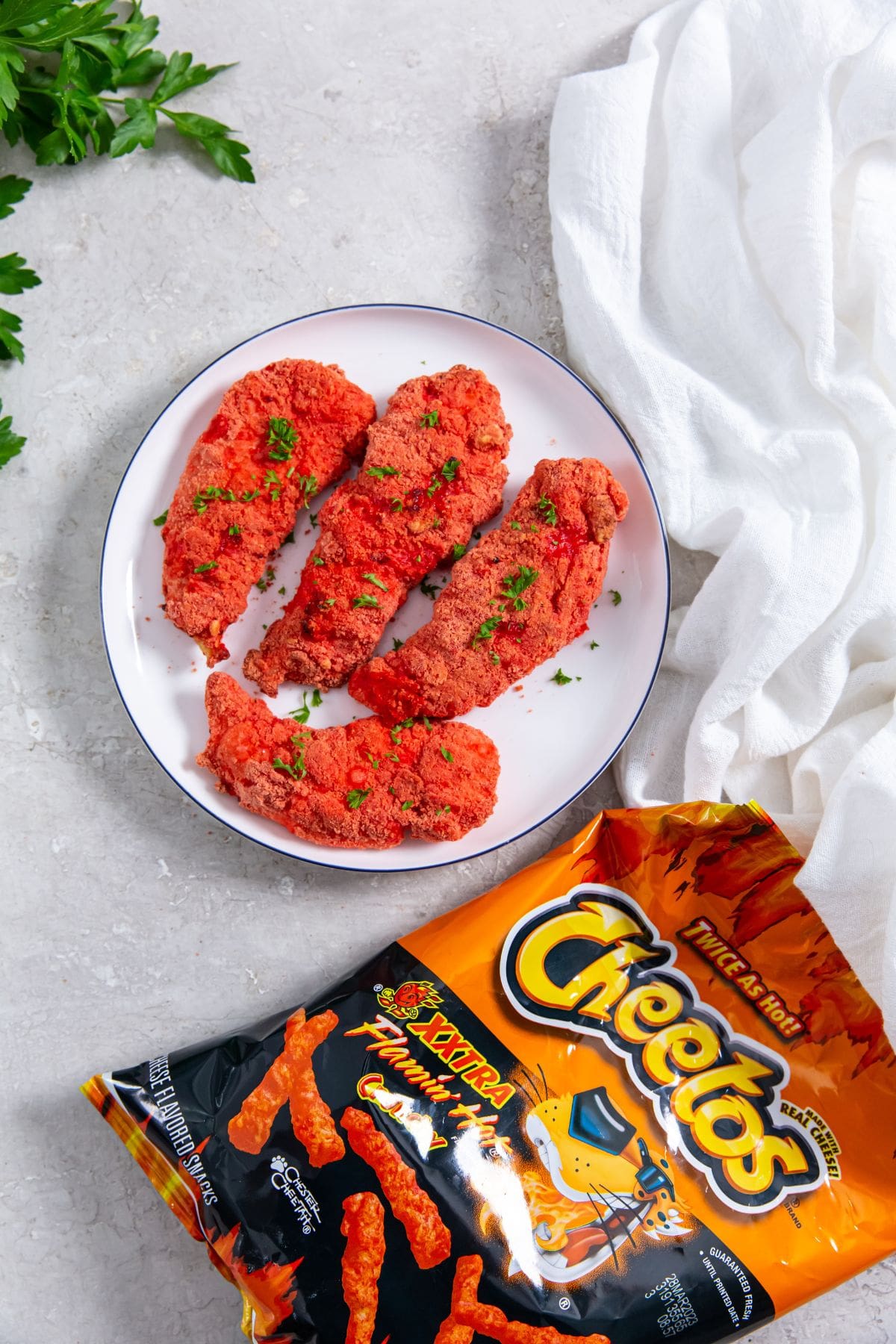Air Fryer Flamin' Hot Cheetos Chicken Tenders chicken on a plate Cheetos bag next to it
