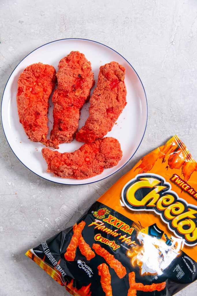 Air Fryer Flamin' Hot Cheetos Chicken Tenders chicken on a plate Cheetos bag next to it