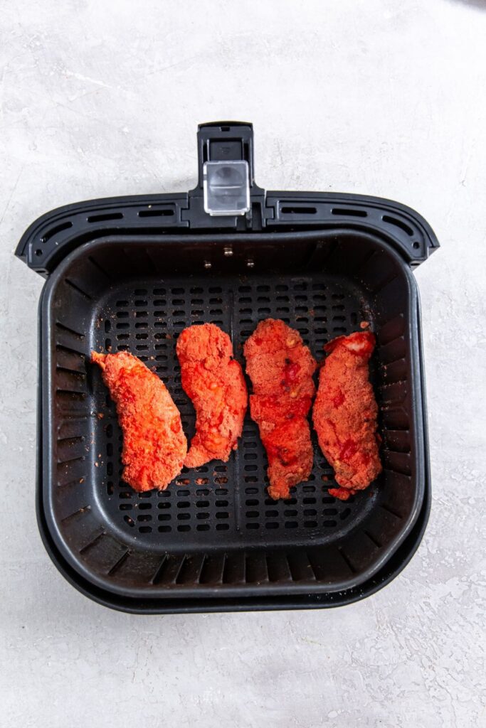 Air Fryer Flamin' Hot Cheetos Chicken Tenders black air fryer with cooked chicken inside