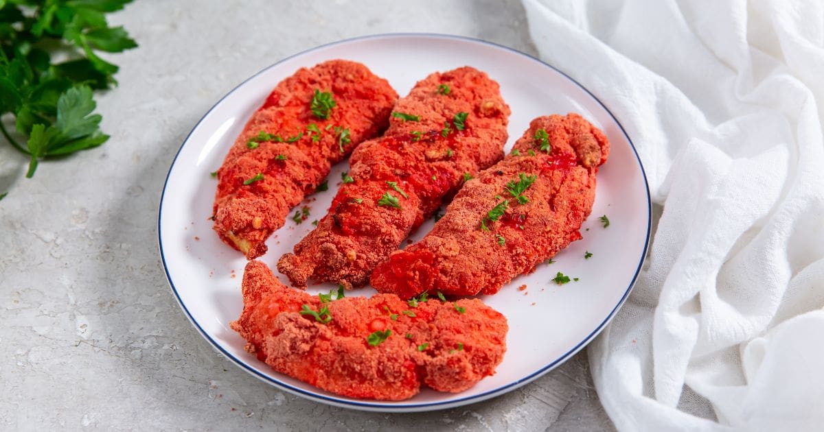 Air Fryer Flamin' Hot Cheetos Chicken Tenders white plate with chicken parsley and white towel next to it