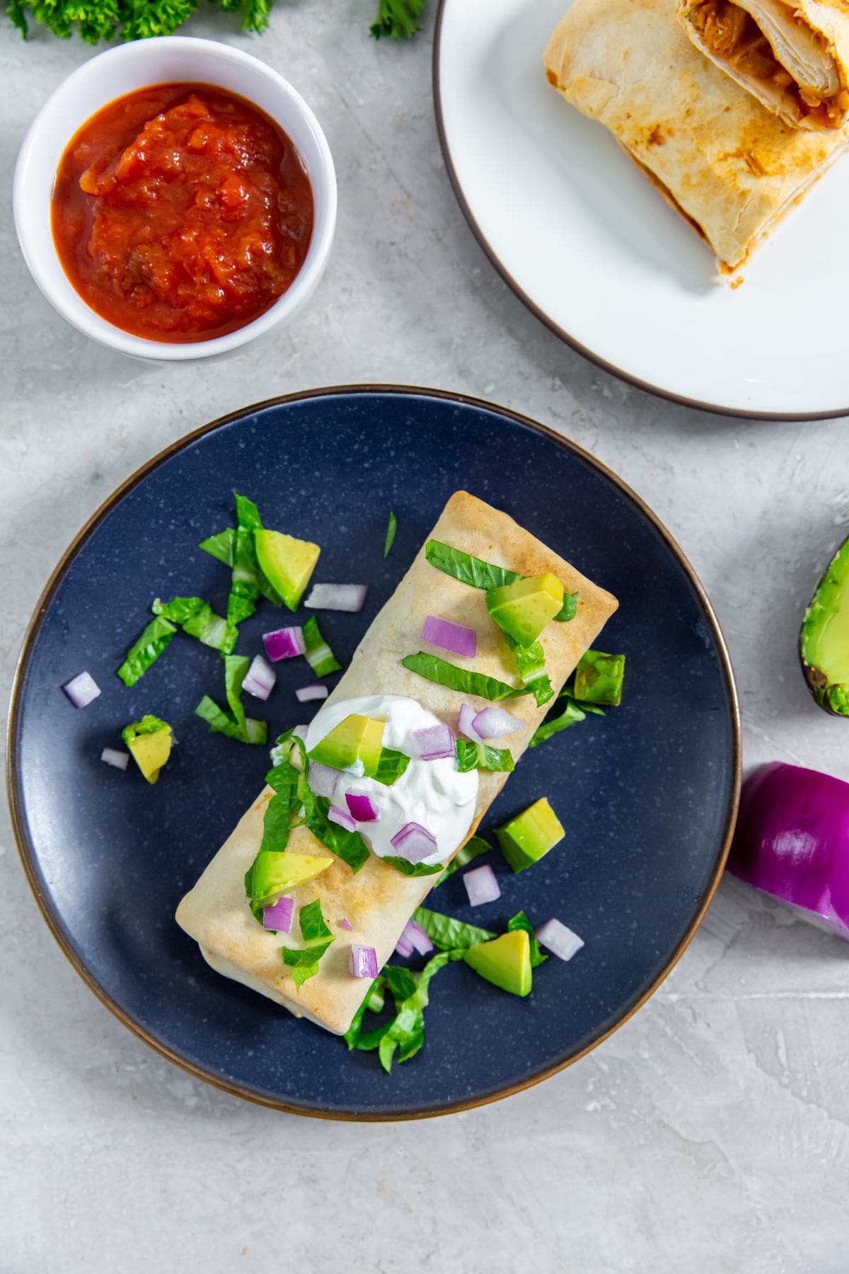 Air Fryer Trader Joes Chicken Burritos burrito with sour cream avocado and lettuce salsa in the back