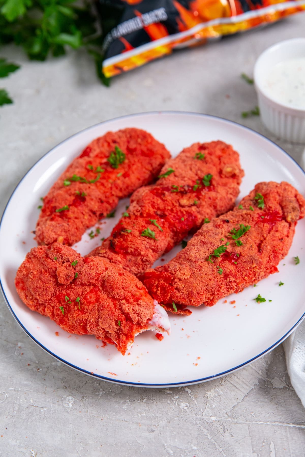 Air Fryer Flamin' Hot Cheetos Chicken Tenders chicken on a plate Cheetos bag next to it