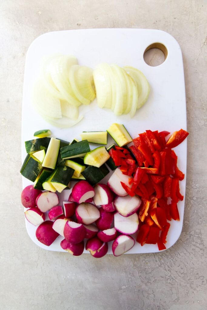 Air Fryer Chicken and Veggies White cutting board with cut up veggies on it