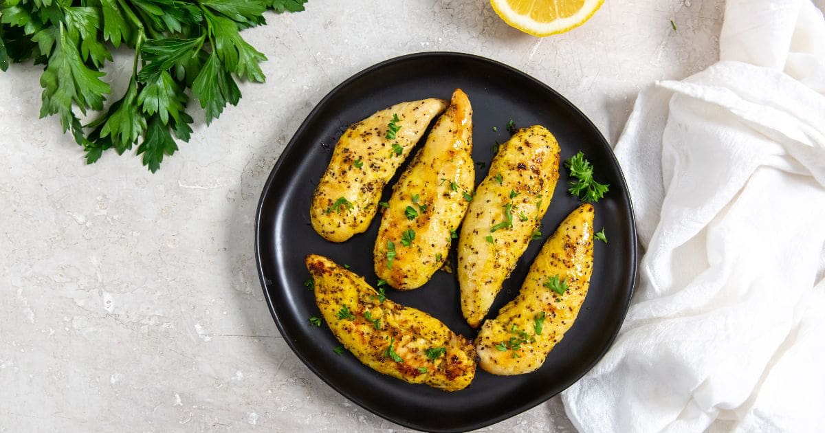 Air Fryer Lemon Pepper Chicken Tenders Black Plate with Lemon Pepper Chicken Tenders On it