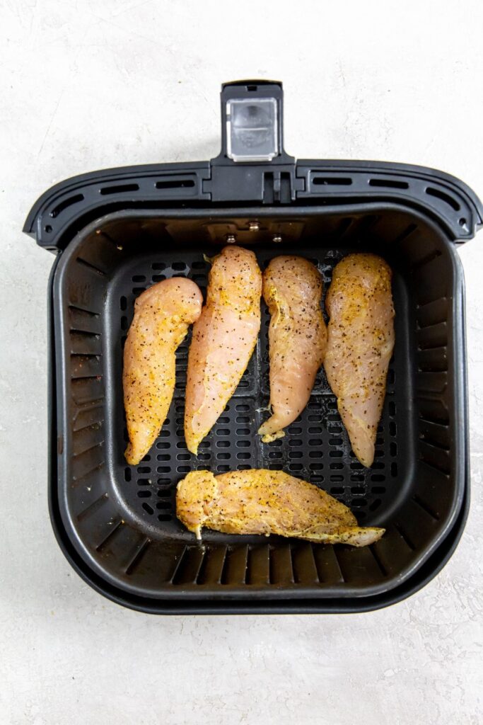 Air Fryer Lemon Pepper Chicken Tenders black air fryer with raw chicken inside