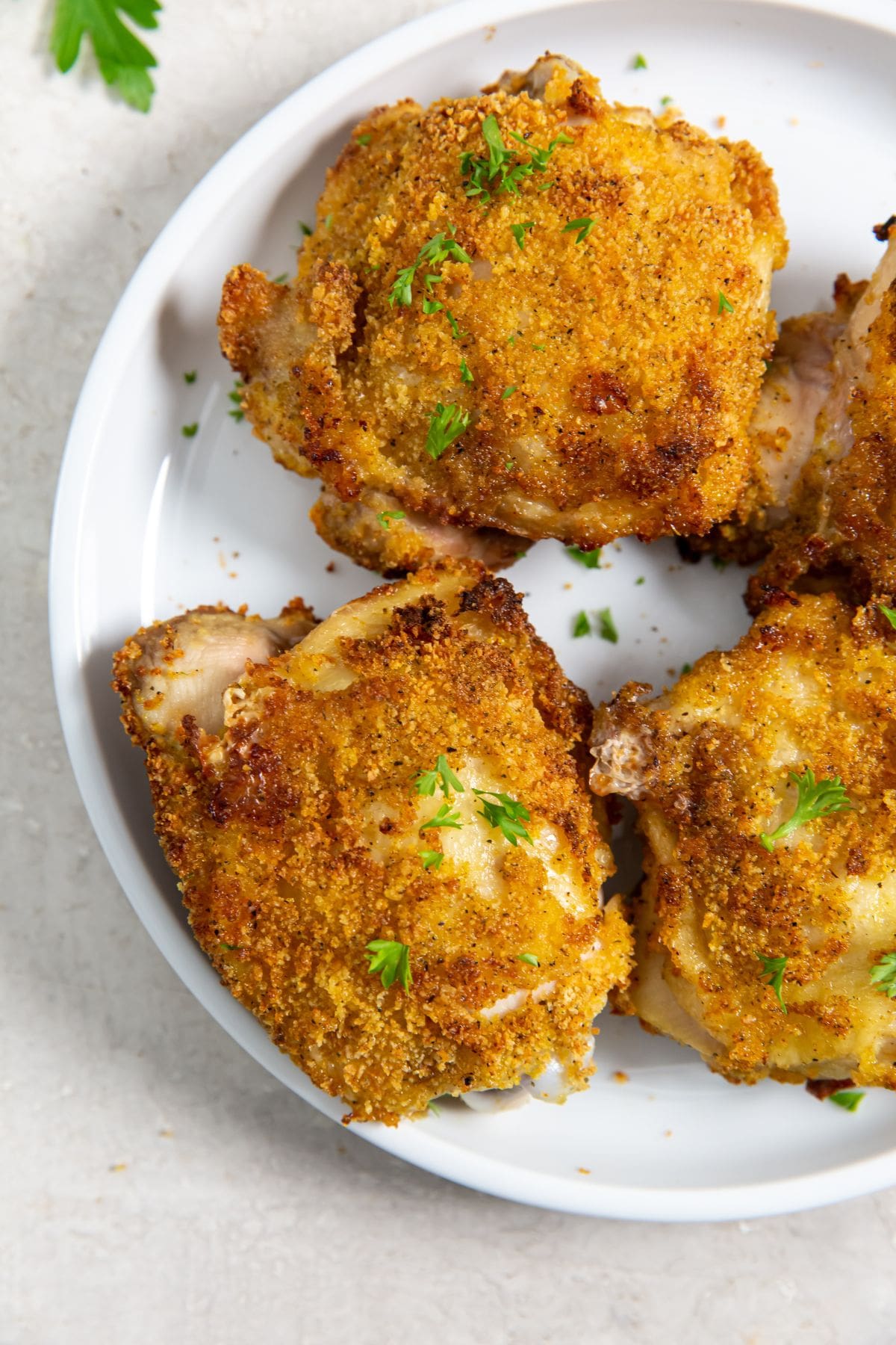 Air Fryer Shake N Bake Chicken Thighs white plate with chicken on it. parsley in the back.