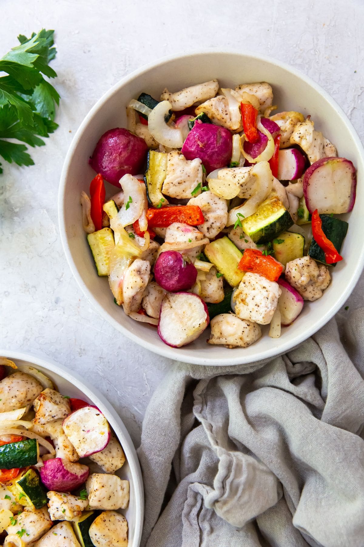 Air Fryer Chicken and Veggies White bowl with chicken and veggies inside it. Gray towel on side