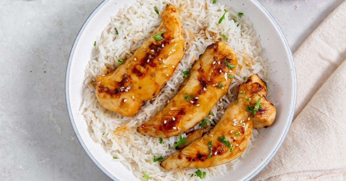 Air Fryer Teriyaki Chicken Tenders white bowl with chicken and rice parsley and towel in the back