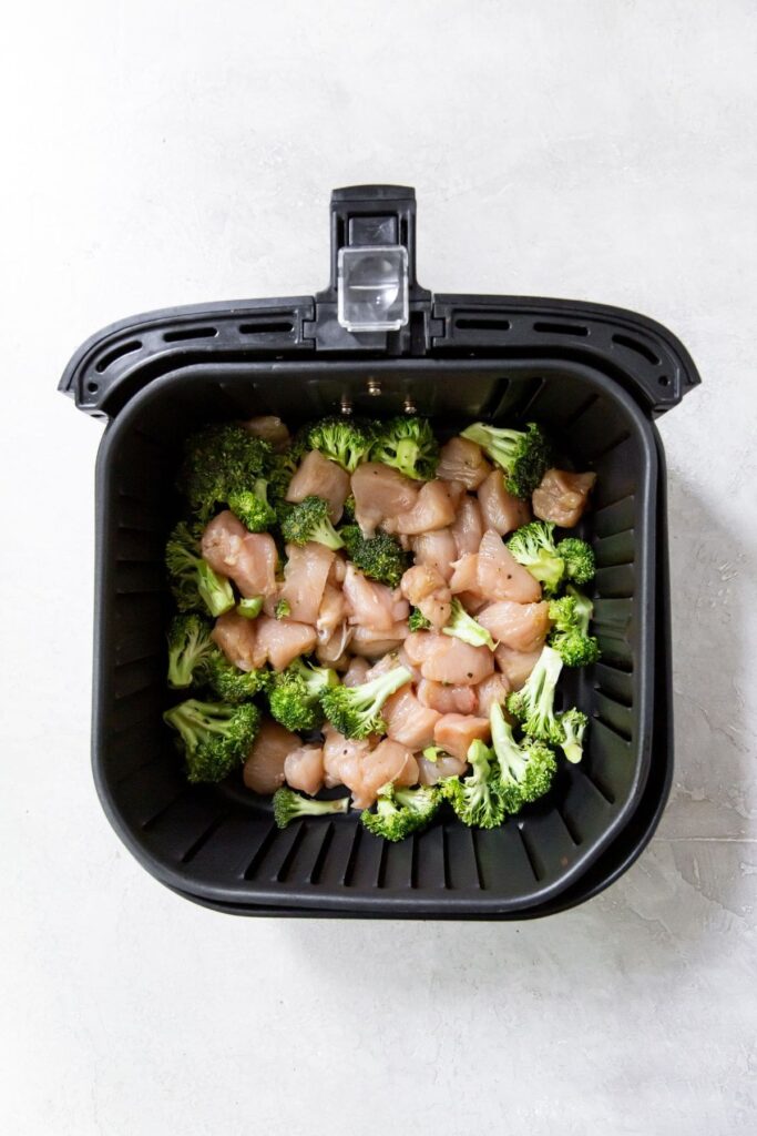 Air Fryer Chicken and Broccoli Black Air fryer with raw chicken and broccoli
