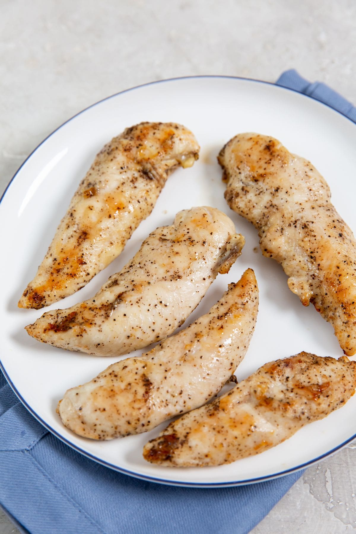 Air Fryer Keto Chicken Tenders chicken on a white plate blue towel underneath