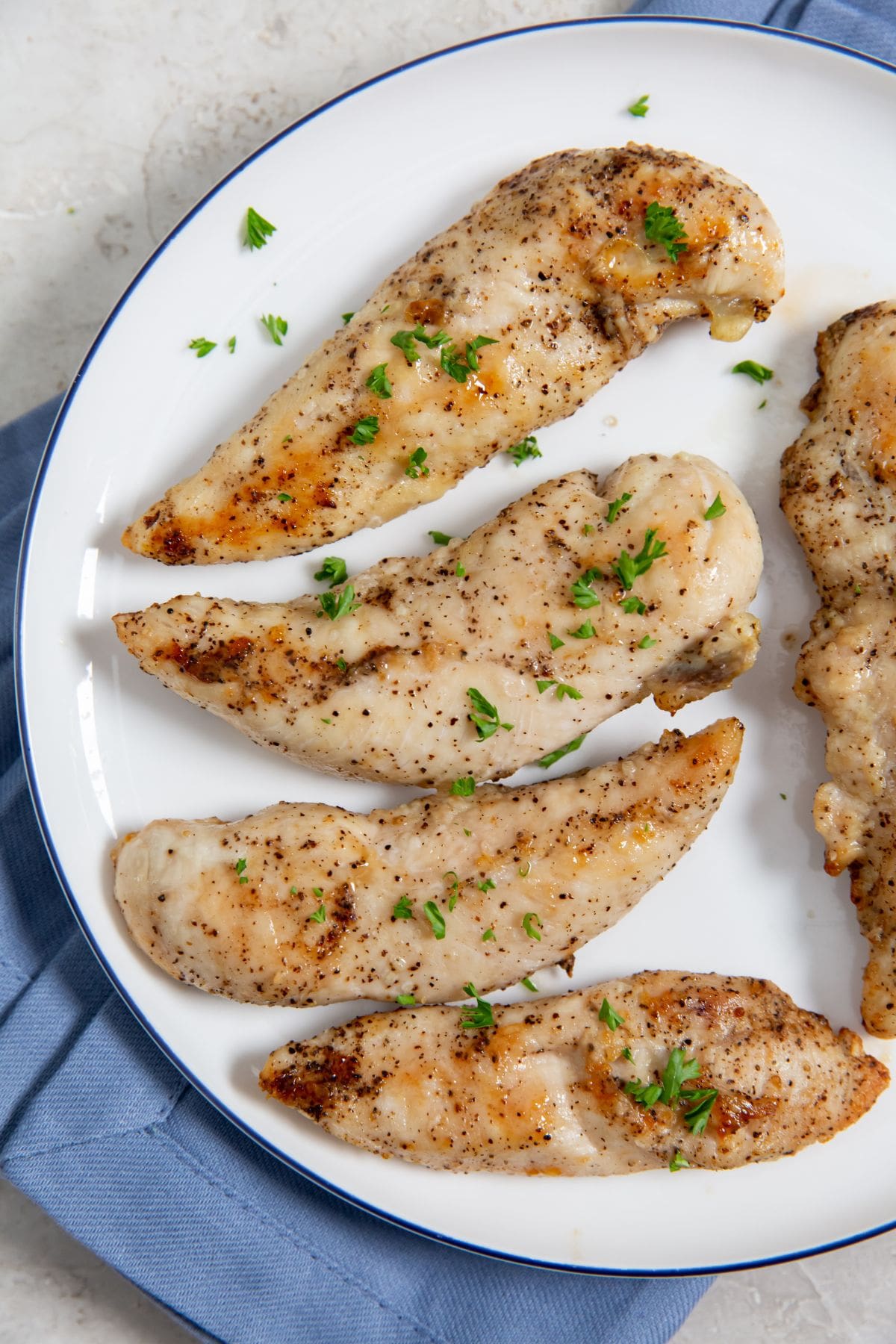 Air Fryer Keto Chicken Tenders on a White Plate with a Blue Towel Underneath