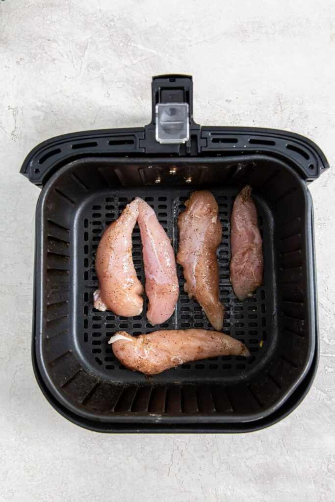 Air Fryer Keto Chicken Tenders black air fryer with raw chicken inside