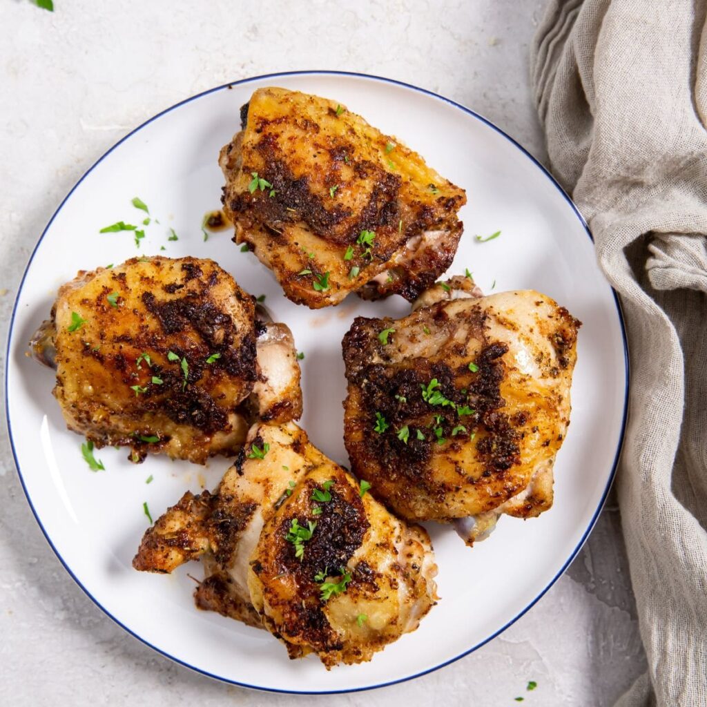 Air Fryer Blackened Chicken Thighs a White Plate with Four Chicken Thighs On Top