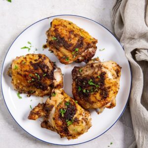 Air Fryer Blackened Chicken Thighs a White Plate with Four Chicken Thighs On Top