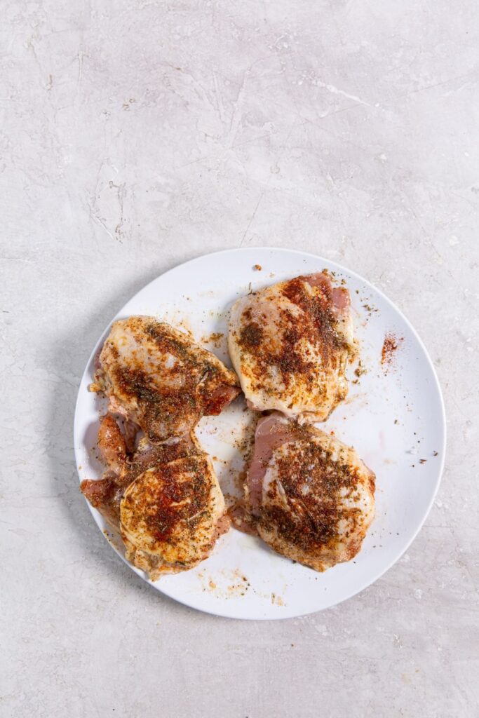 Air Fryer Blackened Chicken Thighs white plate with seasoned chicken on it