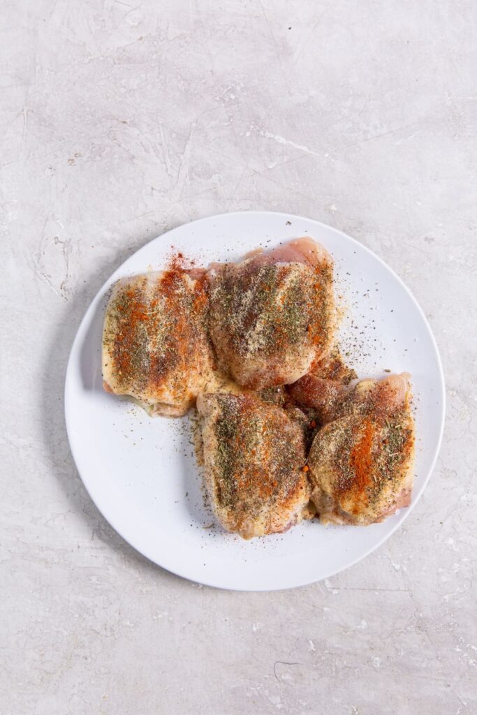 Air Fryer Blackened Chicken Thighs white plate with seasoned chicken on it