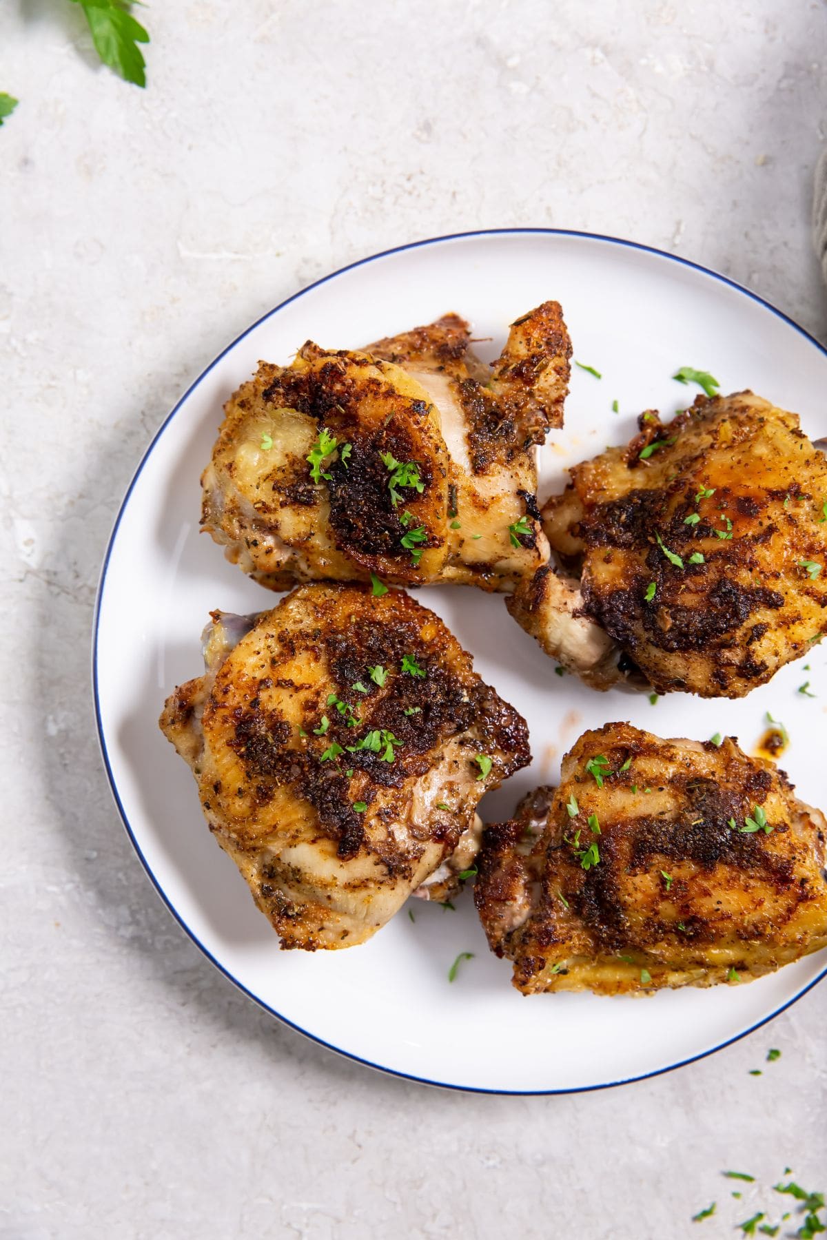 Air Fryer Blackened Chicken Thighs white plate with chicken on it parsley in the back