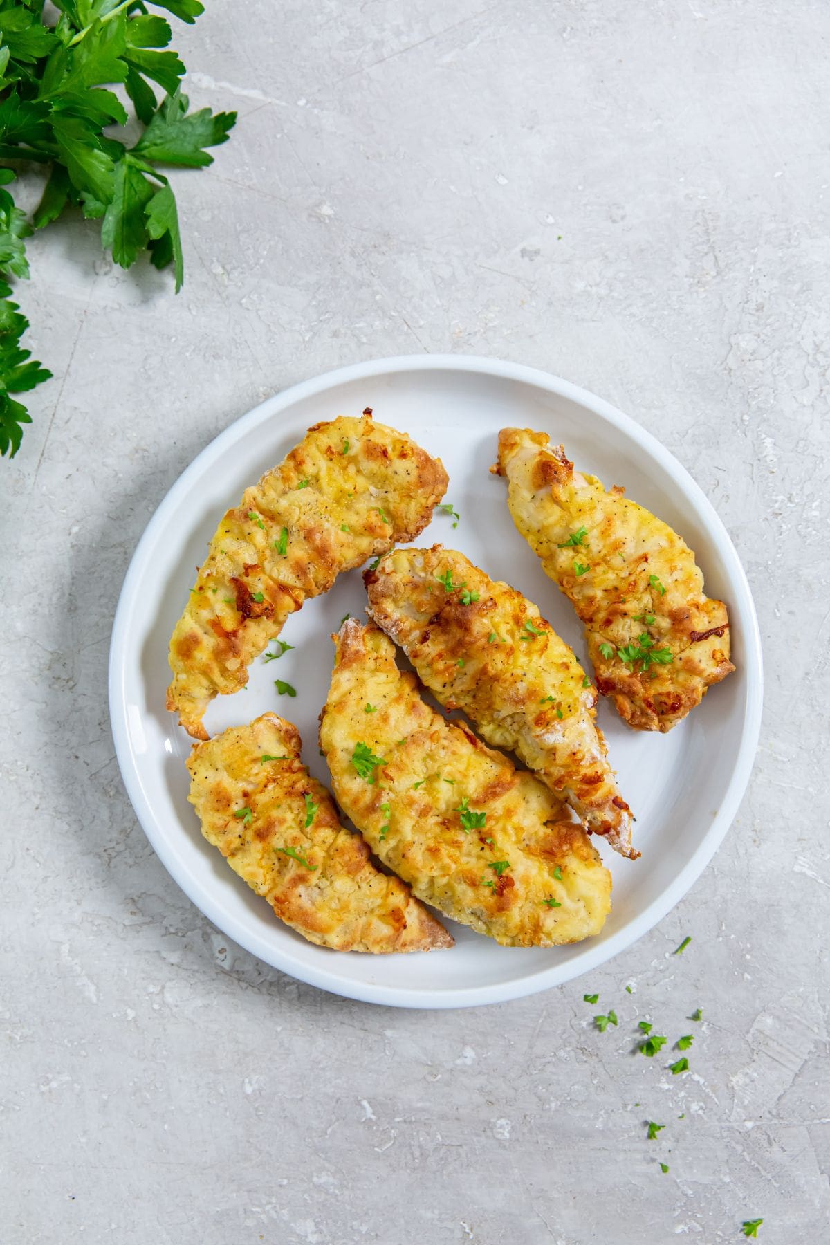 Easy Air Fryer Chicken Tenders With Flour white plate with chicken parsley in the back