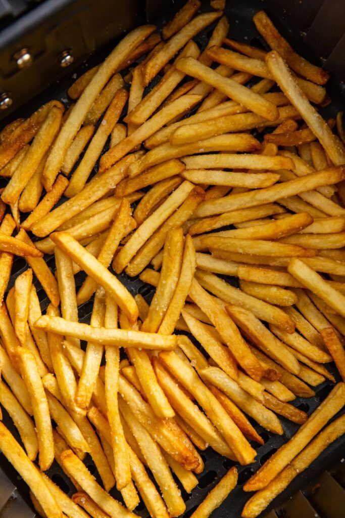 Air Fryer Frozen French Fries black air fryer basket with fries inside.