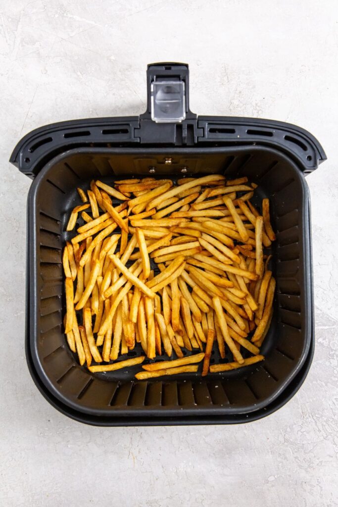 Air Fryer Frozen French Fries black air fryer basket with fries inside.